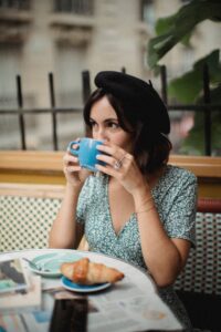 A woman enjoys a coffee at a cozy Paris cafe, embodying a relaxed and stylish lifestyle.